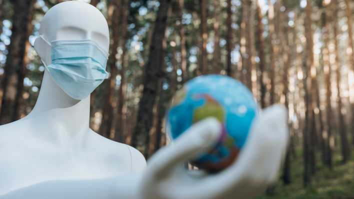Ein Roboter mit medizinischer Maske hält eine Weltkugel in seiner Hand (Bild: picture alliance/Westend61/Jose Carlos Ichiro)